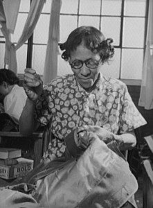 Quartermaster Depot photograph of a woman stitching sleeves on an army overcoat